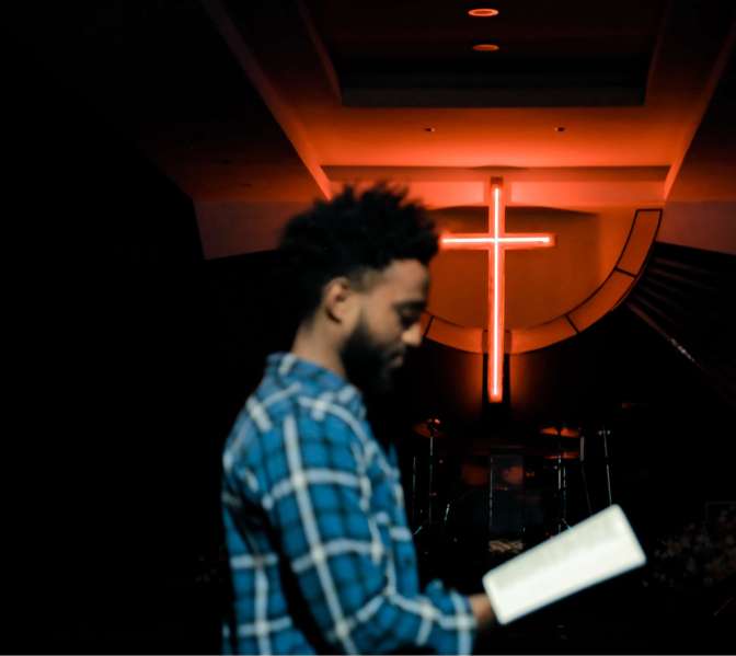 This photo is of a man standing in a mostly-dark church (except for a bright white-and-orange cross in the background), holding and reading a Bible. The basic moral values found in the Bible that pertain to human interactions—values that most people believe to be objectively-true (particularly in the Ten Commandments and in the Sermon on the Mount)—mirror the SAME moral values found in the human heart. (Cf. Exodus 20:1-17; Deuteronomy 5:6-21; Matthew 5:1-7:27)